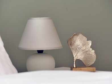 Die Nachttischlampe und ein Ginkgoblatt aus Metall im Schlafzimmer der Ferienwohnung in der Region Mittelrhein.