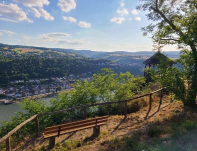 Blick ins Rheintal auf St. Goar und die Burg Rheinfels, im Vordergrund eine Aussichtsbank und ein Aussichtshäuschen, Abendstimmung
