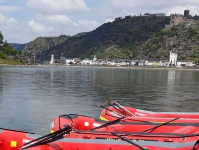 rote Boote im Vordergrund von Mittelrhein-Rafting, im Hintergrund St. Goarshausen