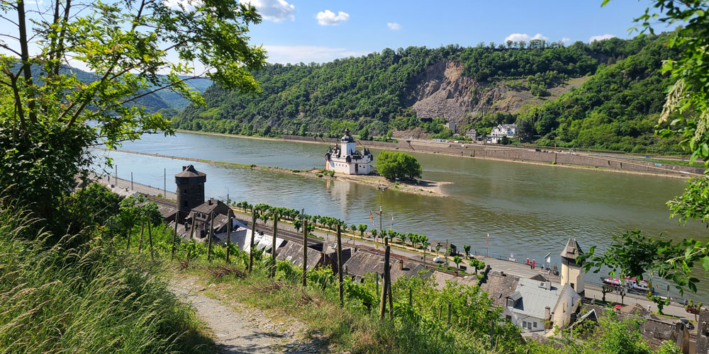 Blick ins Mittelrheintal auf die Burg Pfalzgrafenstein mit einem Wanderweg im Vordergrund